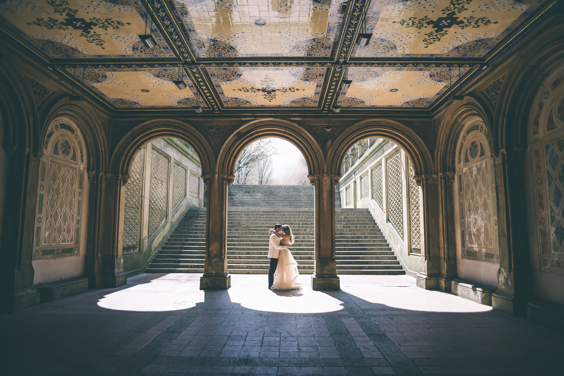 A couple embracing beneath the arches of Bethesda Terrace